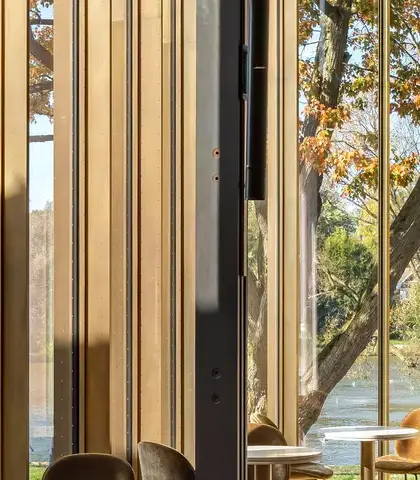 moderne interieurruimte met grote glazen ramen, die een uitzicht biedt op een serene oeverlandschap met bomen