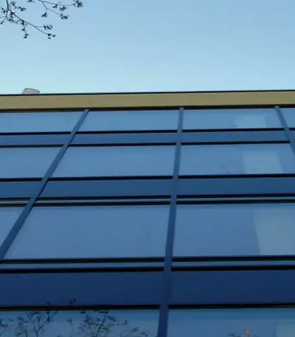 een modern gebouw met grote glazen gevels die reflecteren tegen een heldere blauwe lucht